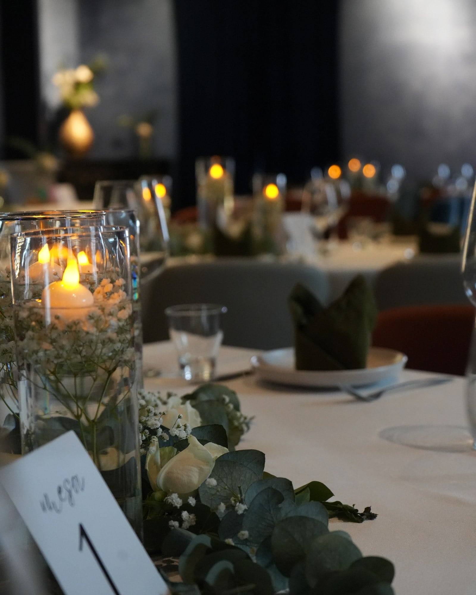 Centro de mesa con velas flotantes, rosas blancas y eucalipto
