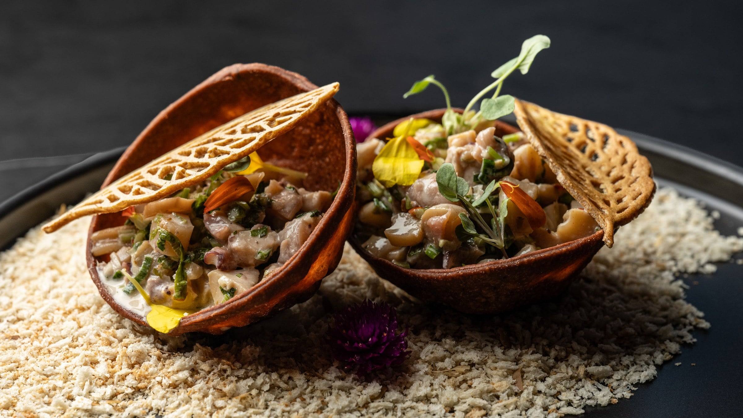 Dos tostadas de ceviche con flores comestibles y brotes